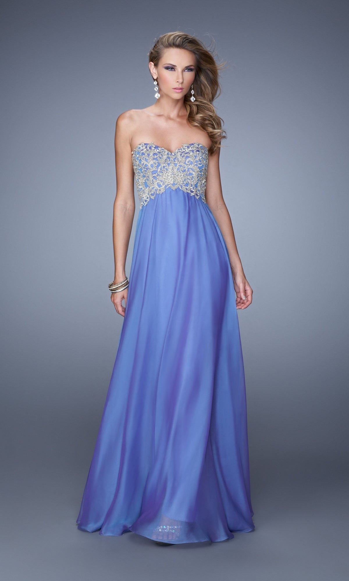 A woman poses against a plain gray background wearing the La Femme Embroidered Chiffon Prom Dress 21289, featuring a strapless design with a beaded, embroidered bodice.
